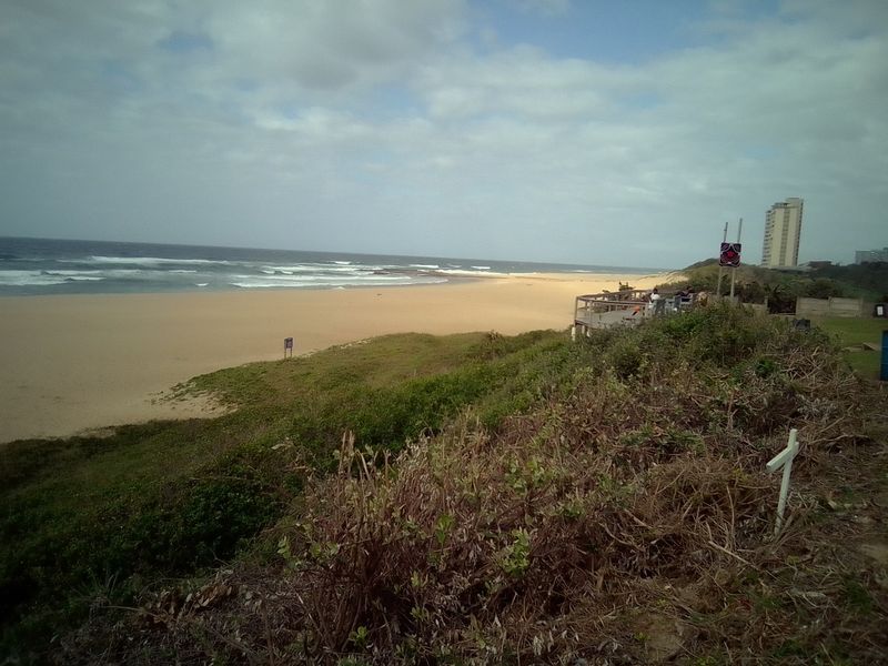 A scenic coastal view overlooking the sandy beach and ocean, showcasing the property's proximity to the shoreline.