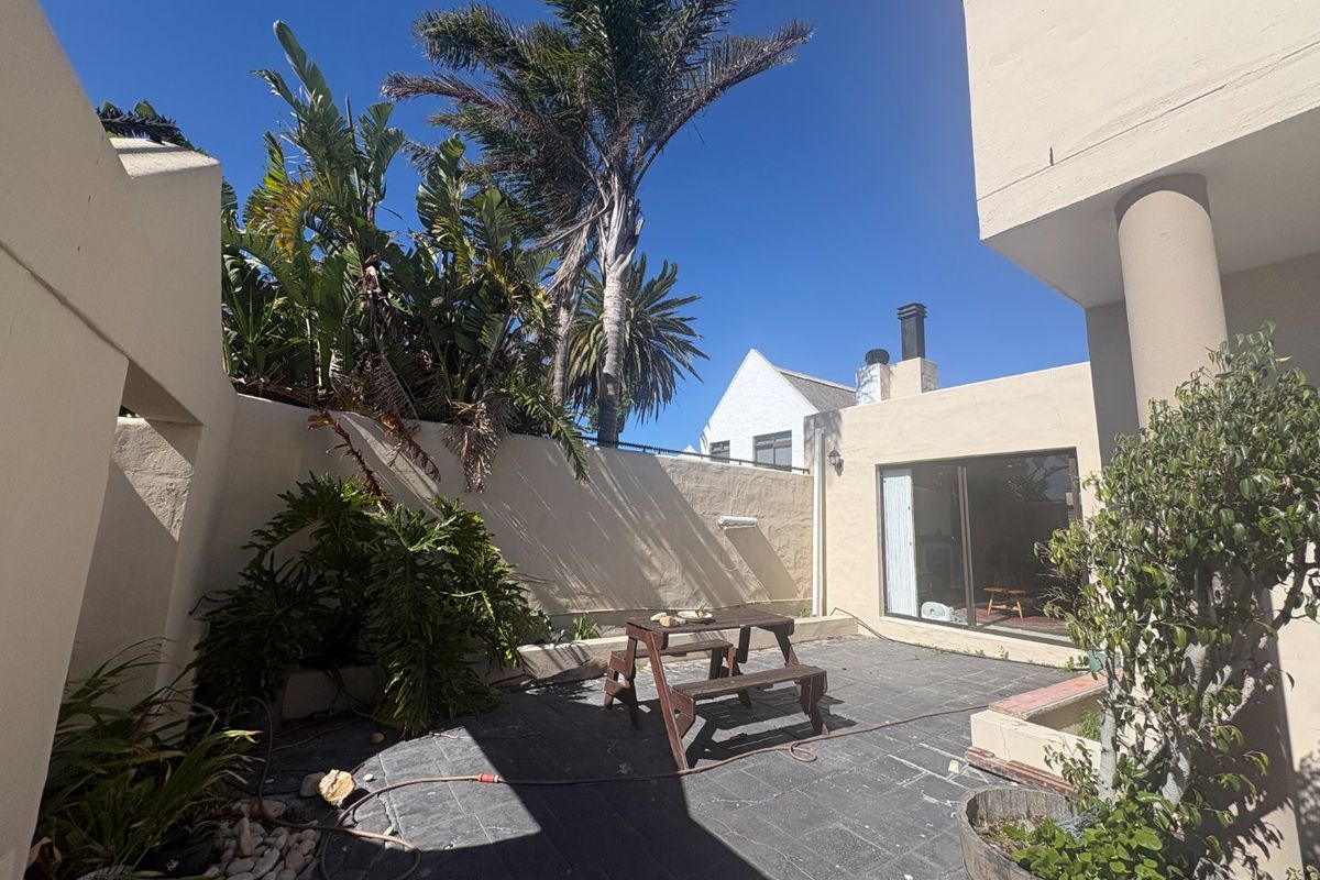 A private rear courtyard featuring paved flooring, boundary walls, and direct access to the interior via a sliding glass door.