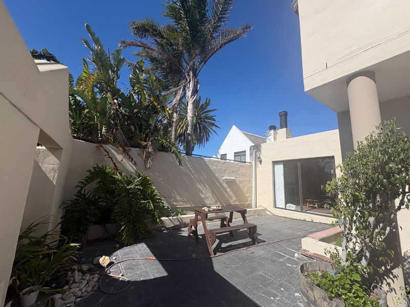 A private rear courtyard featuring paved flooring, boundary walls, and direct access to the interior via a sliding glass door.