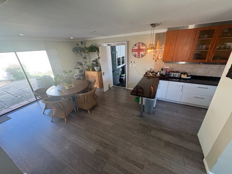 Open-plan kitchen and dining area featuring modern laminate flooring, granite countertops, and direct access to an outdoor patio through sliding glass doors.