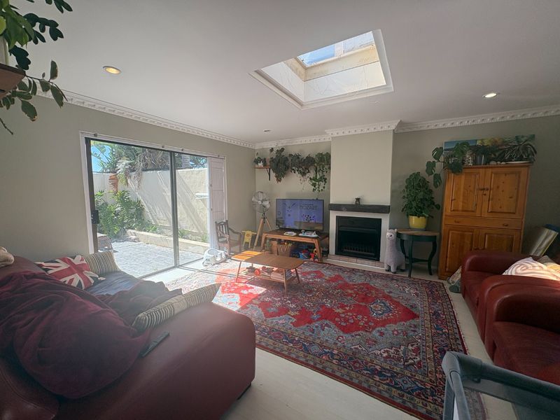 Spacious living room featuring a fireplace, crown molding, recessed lighting, and a large skylight, with sliding glass doors providing access to the outdoor area.