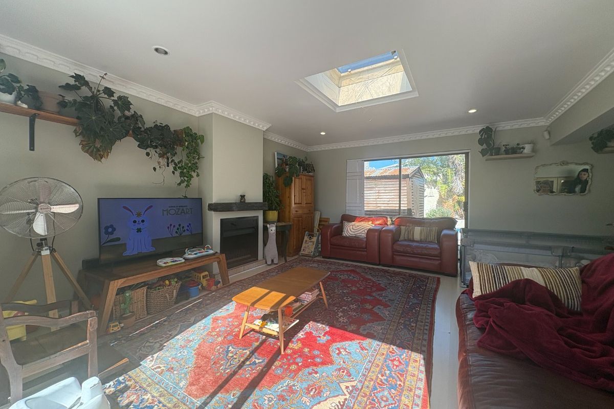 A comfortable living room featuring a fireplace, crown molding, and a skylight that provides ample natural light, with direct access to the outdoor area.