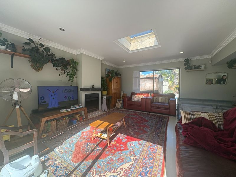 A comfortable living room featuring a fireplace, crown molding, and a skylight that provides ample natural light, with direct access to the outdoor area.