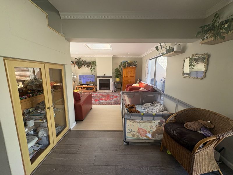 Spacious living room featuring a built-in fireplace, skylight, crown molding, and laminate flooring, offering a comfortable and well-lit living space.