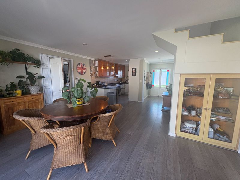 Open-plan living and dining area featuring laminate flooring, a functional kitchen with built-in appliances, and a staircase leading to the upper level.