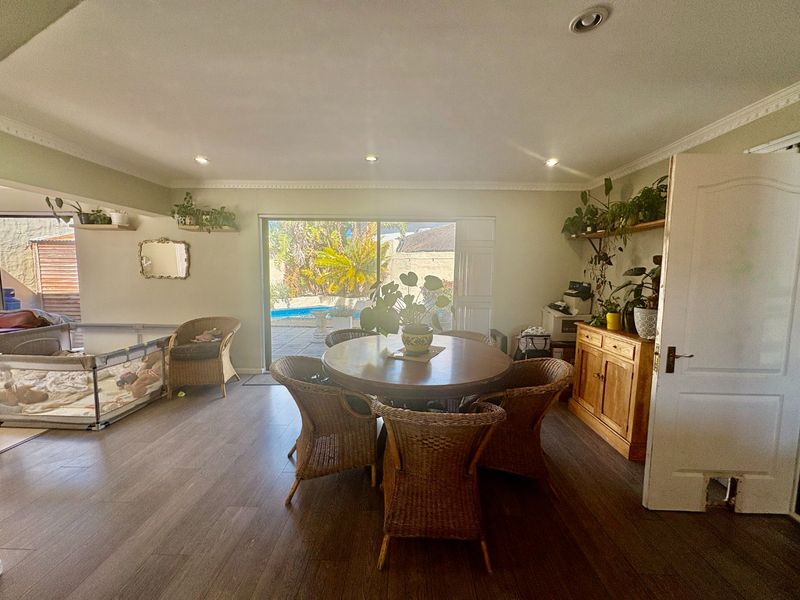 Spacious living area featuring laminate flooring, recessed lighting, and sliding glass doors providing direct access to the outdoor pool area.