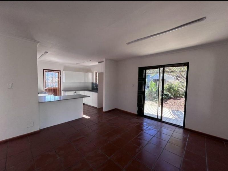 Open plan living and kitchen area featuring tiled flooring, white cabinetry, and sliding glass doors providing direct access to the outdoor space.