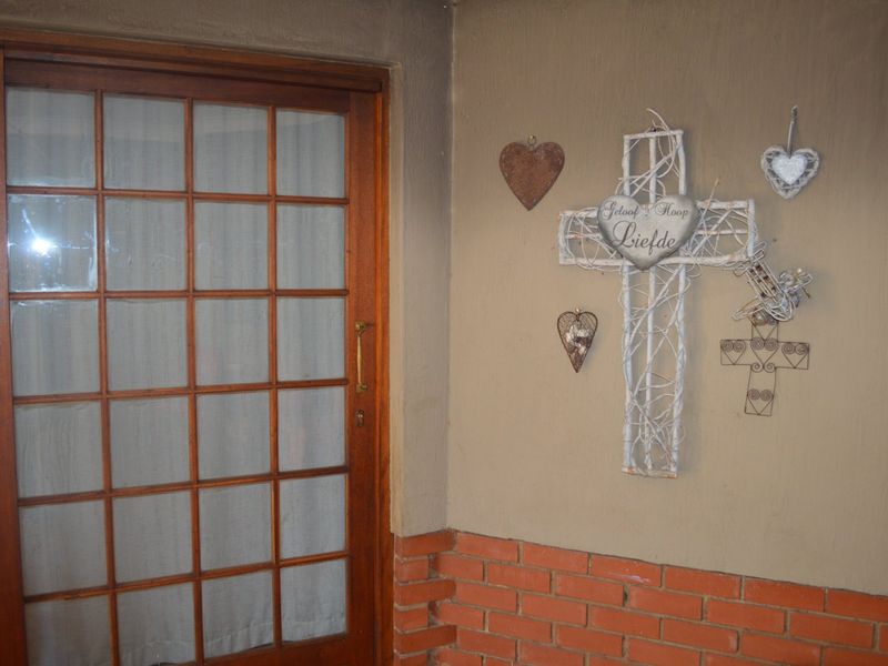 A covered patio area featuring a wooden sliding door and a combination of brick and plastered wall finishes.