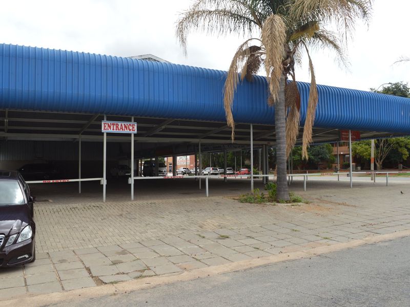 Commercial property frontage featuring a large covered parking area with a blue corrugated metal roof and paved driveway access.