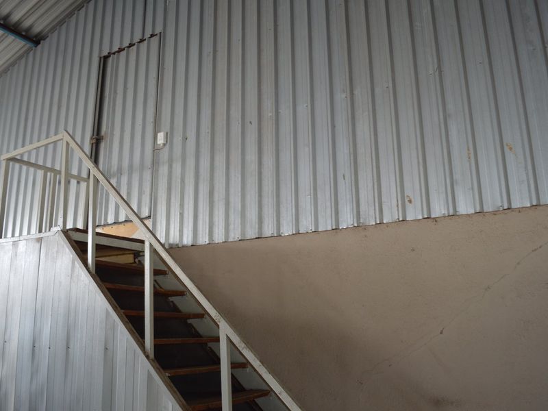 Industrial utility space featuring corrugated metal wall cladding and a functional metal staircase leading to an elevated access door.