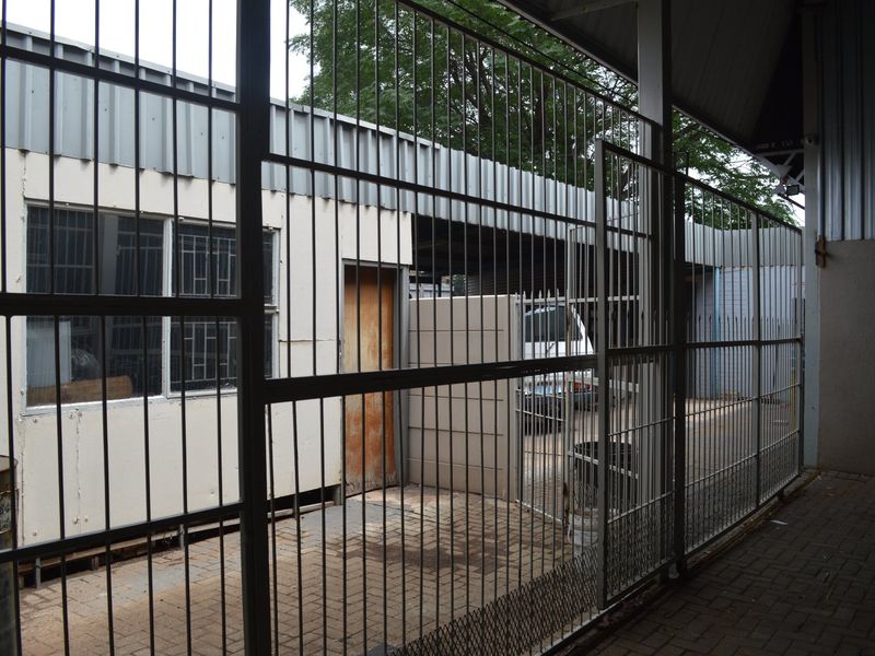 A secure, paved rear courtyard area featuring metal roofing, security fencing, and gated access to the commercial property.