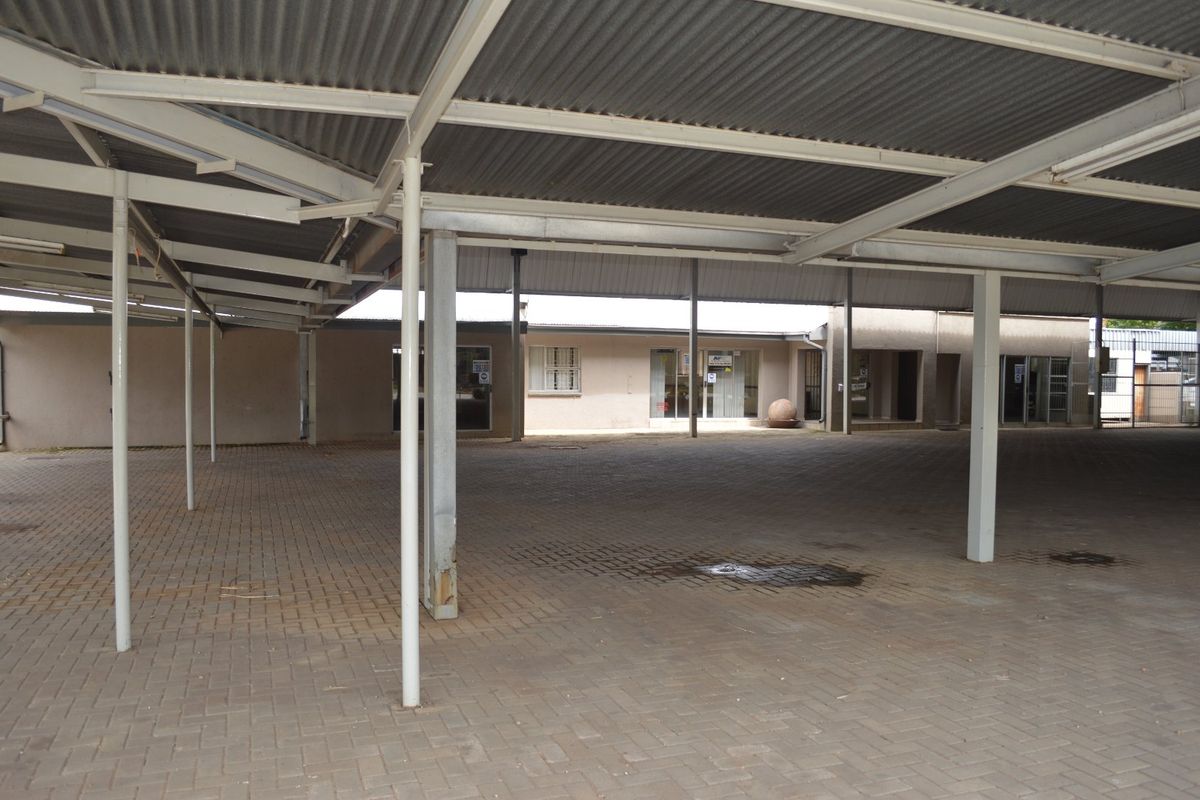 A large, covered paved courtyard area featuring a corrugated metal roof supported by steel columns, providing ample outdoor space for commercial use.