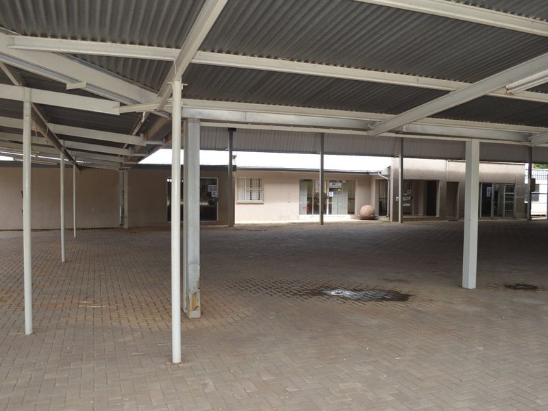 A large, covered paved courtyard area featuring a corrugated metal roof supported by steel columns, providing ample outdoor space for commercial use.