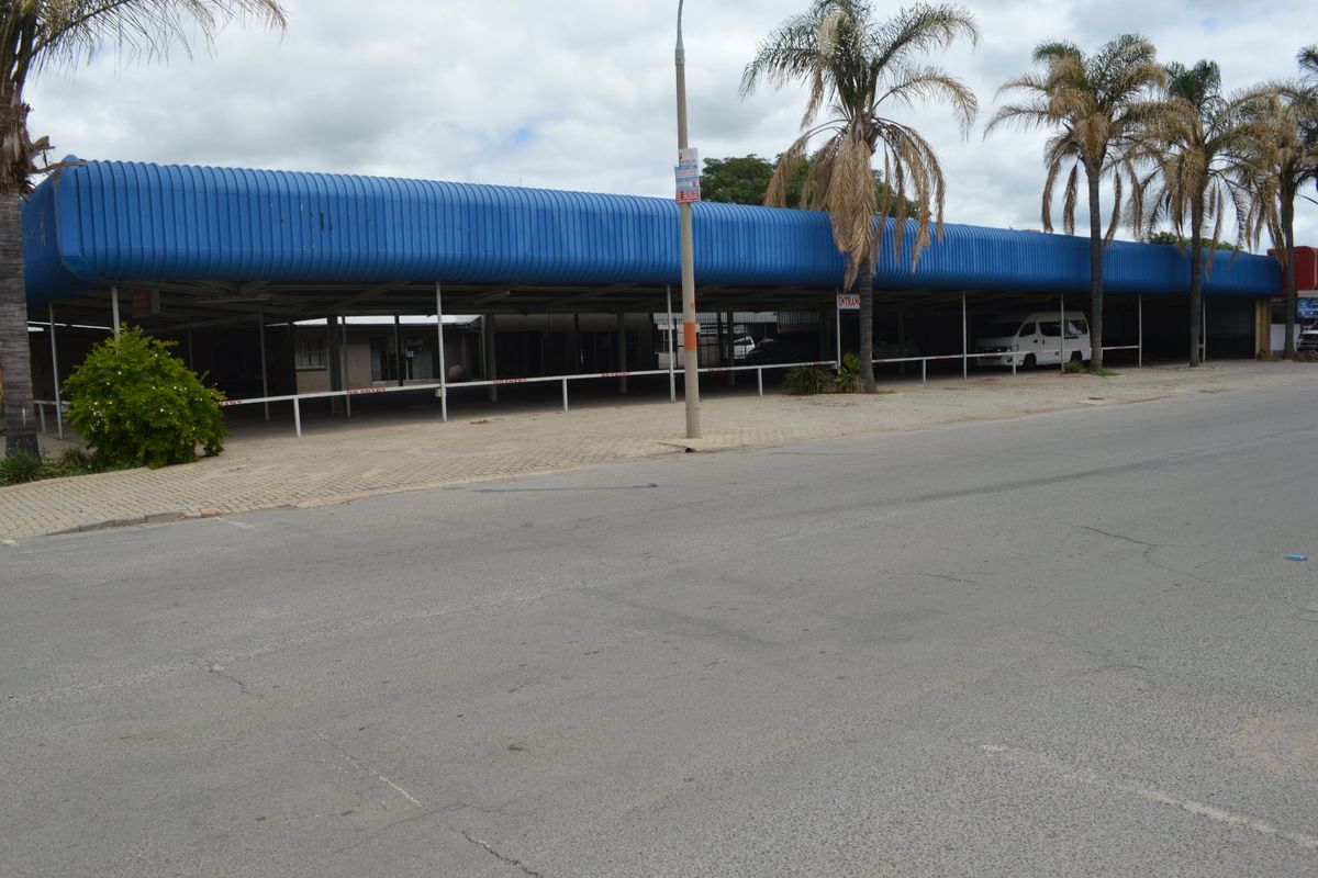 Commercial property exterior featuring a large covered parking area with a blue corrugated metal roof and paved frontage.