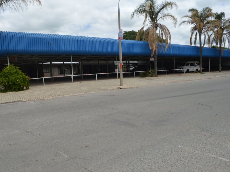 Commercial property exterior featuring a large covered parking area with a blue corrugated metal roof and paved frontage.