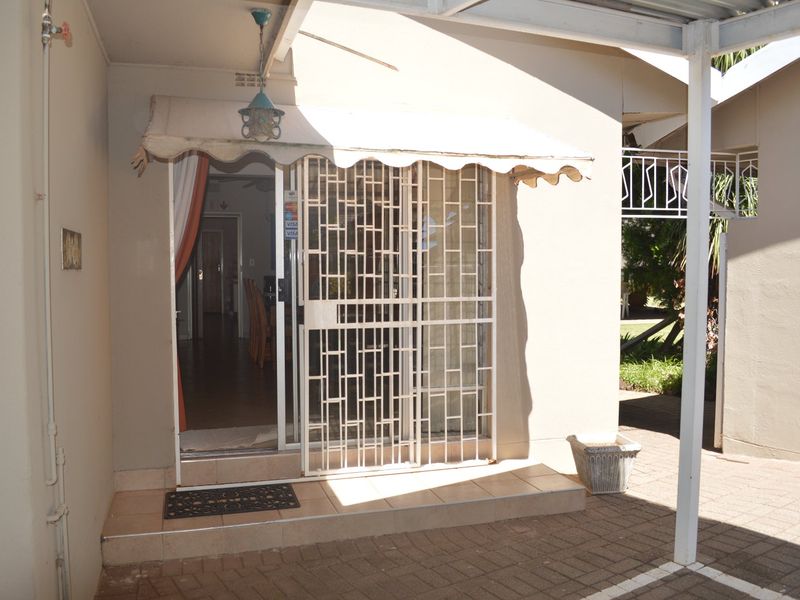 A covered patio area featuring paved flooring, a security gate, and a retractable awning, providing a functional outdoor transition space.