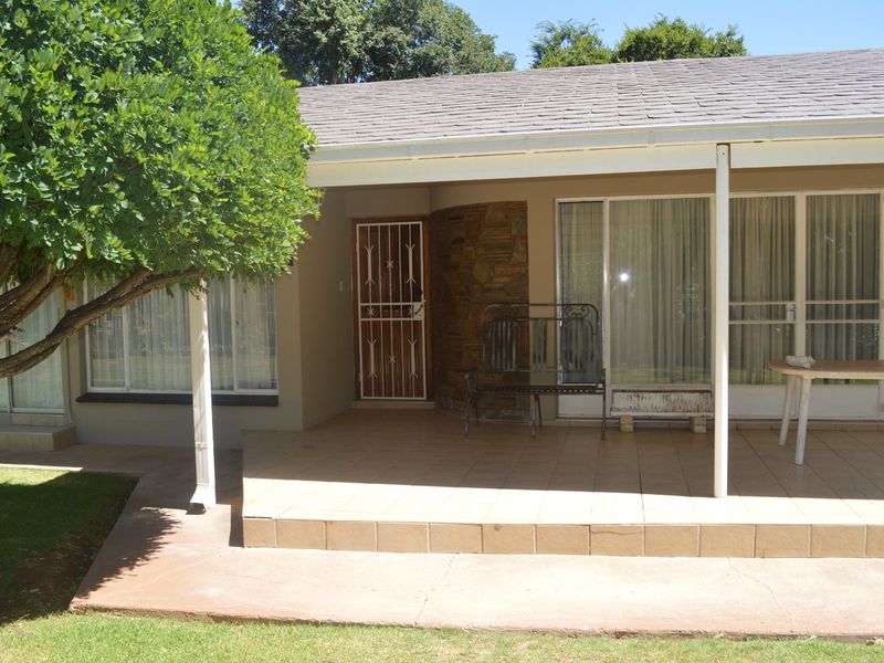 A covered patio area featuring tiled flooring, a stone accent wall, and sliding glass door access to the interior.