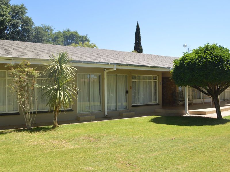 Rear exterior view of the commercial property featuring a paved patio, sliding glass doors, and well-maintained lawn area.