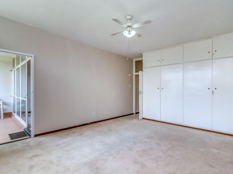 Spacious bedroom featuring built-in cupboards, a ceiling fan, and direct access to an adjoining balcony area.