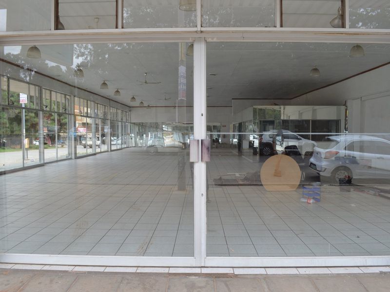 Spacious open-plan commercial retail space featuring large glass storefront windows, tiled flooring, and a suspended ceiling with integrated lighting.