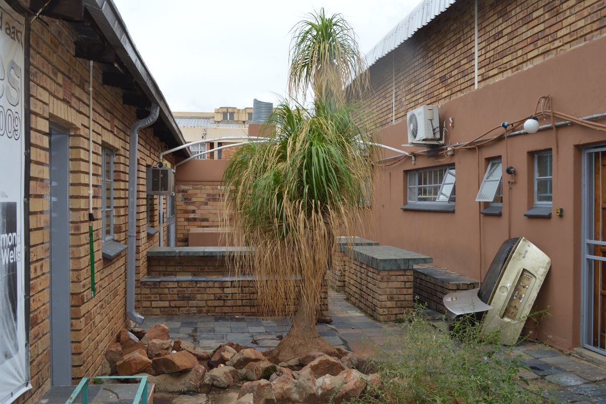A rear courtyard area featuring brick masonry walls, built-in brick seating, and paved flooring, offering a functional outdoor space for the commercial property.