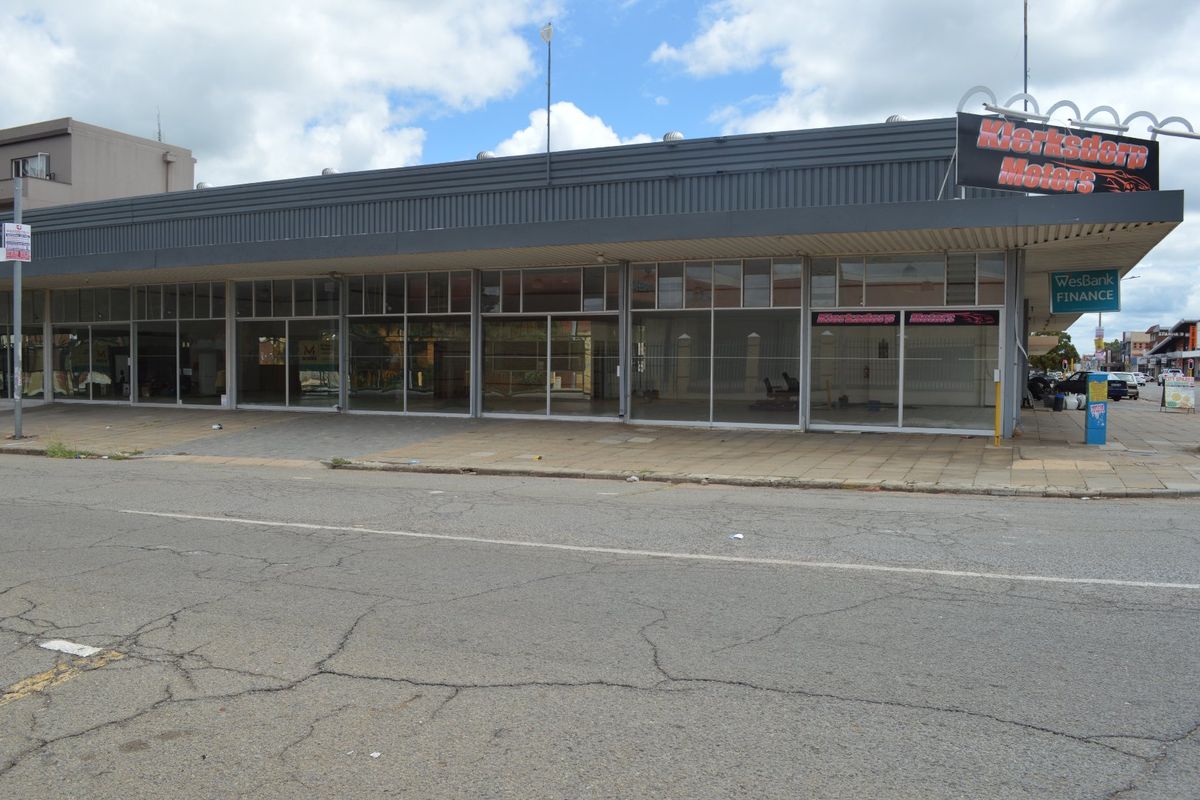 Commercial storefront featuring a large glass facade, metal fascia, and prominent signage, situated along a paved street.