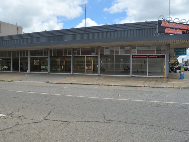 Commercial storefront featuring a large glass facade, metal fascia, and prominent signage, situated along a paved street.