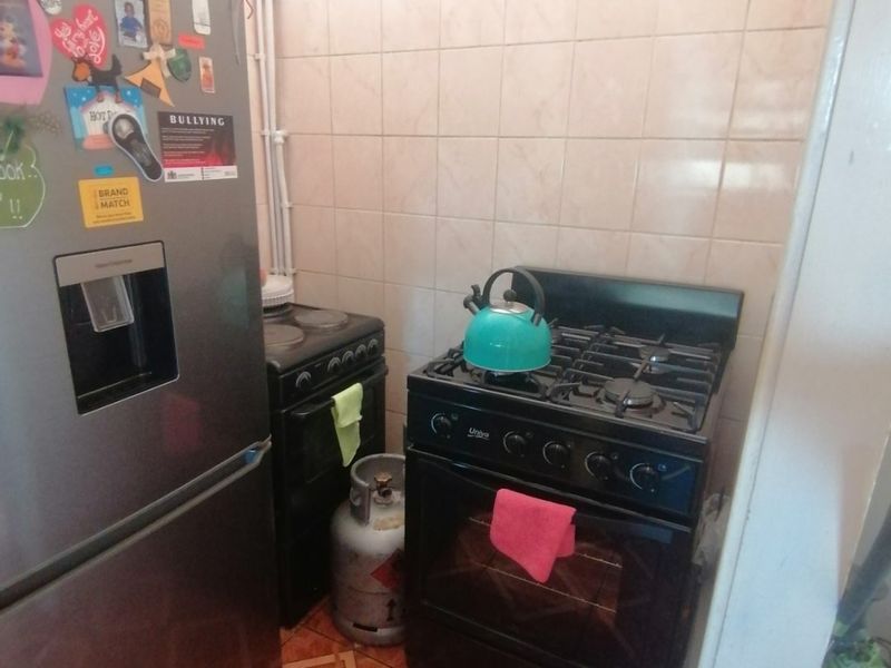 A compact kitchen area featuring a gas stove, tiled backsplash, and tiled flooring, providing a functional cooking space.