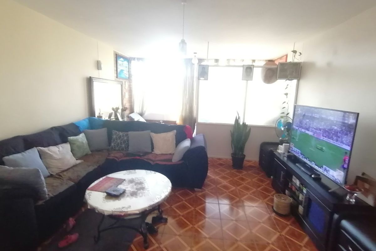A living room featuring tiled flooring and a large window that provides natural light to the space.