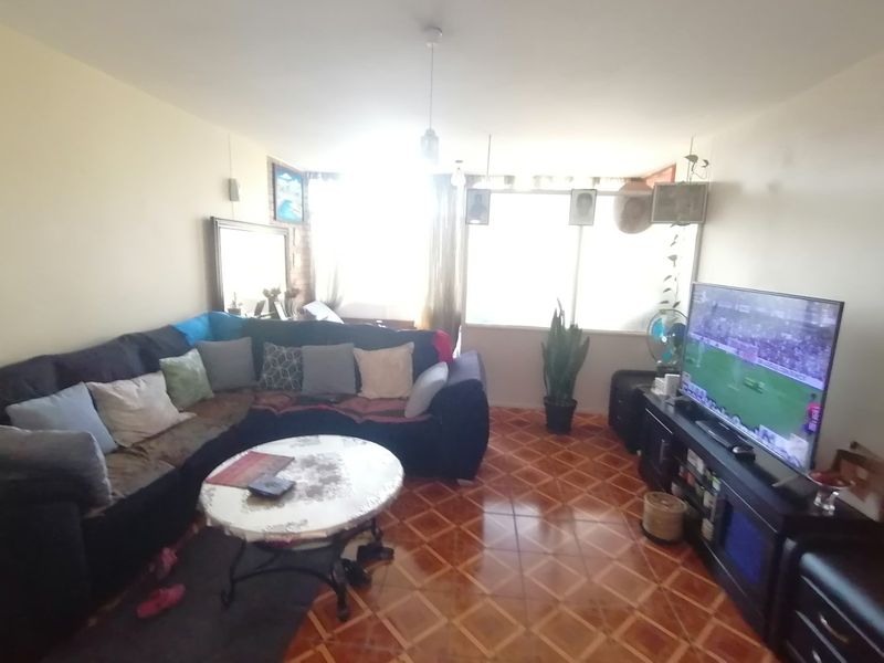 A living room featuring tiled flooring and a large window that provides natural light to the space.