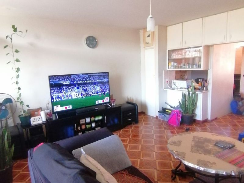Open plan living area featuring parquet flooring and built-in cabinetry, providing a functional space that connects the living room and kitchen area.