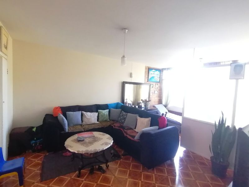 A living room featuring tiled flooring and an exposed brick accent wall, offering a functional space with natural light from the adjacent window area.
