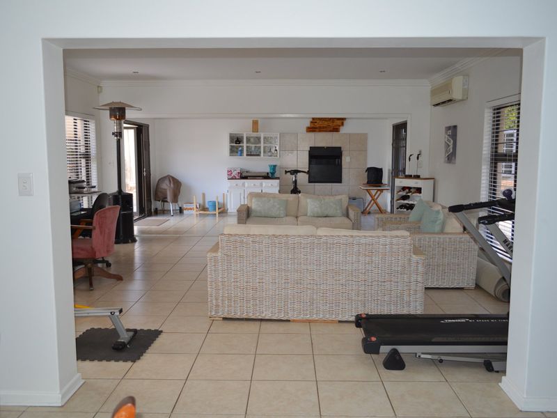 Spacious open-plan living area featuring tiled flooring, a built-in fireplace, and wall-mounted air conditioning, offering a versatile layout for relaxation and entertainment.
