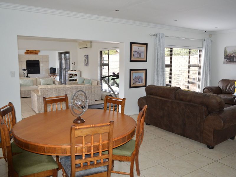 Spacious open-plan living and dining area featuring tiled flooring, recessed lighting, and large windows, creating a bright and functional multi-purpose family space.