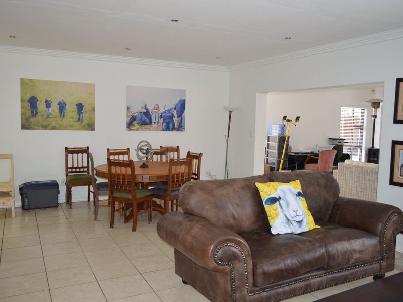 Spacious open-plan living and dining area featuring neutral walls, coved cornicing, recessed downlights, and durable ceramic floor tiles throughout.