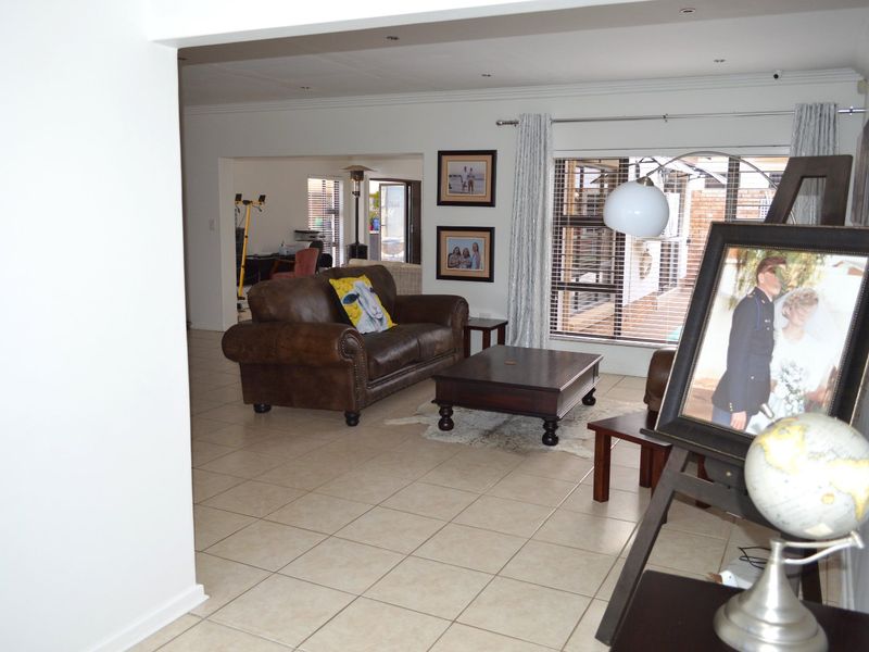 Spacious open-plan living area featuring neutral tiled flooring, recessed lighting, and large sliding glass doors providing access to the outdoor space.
