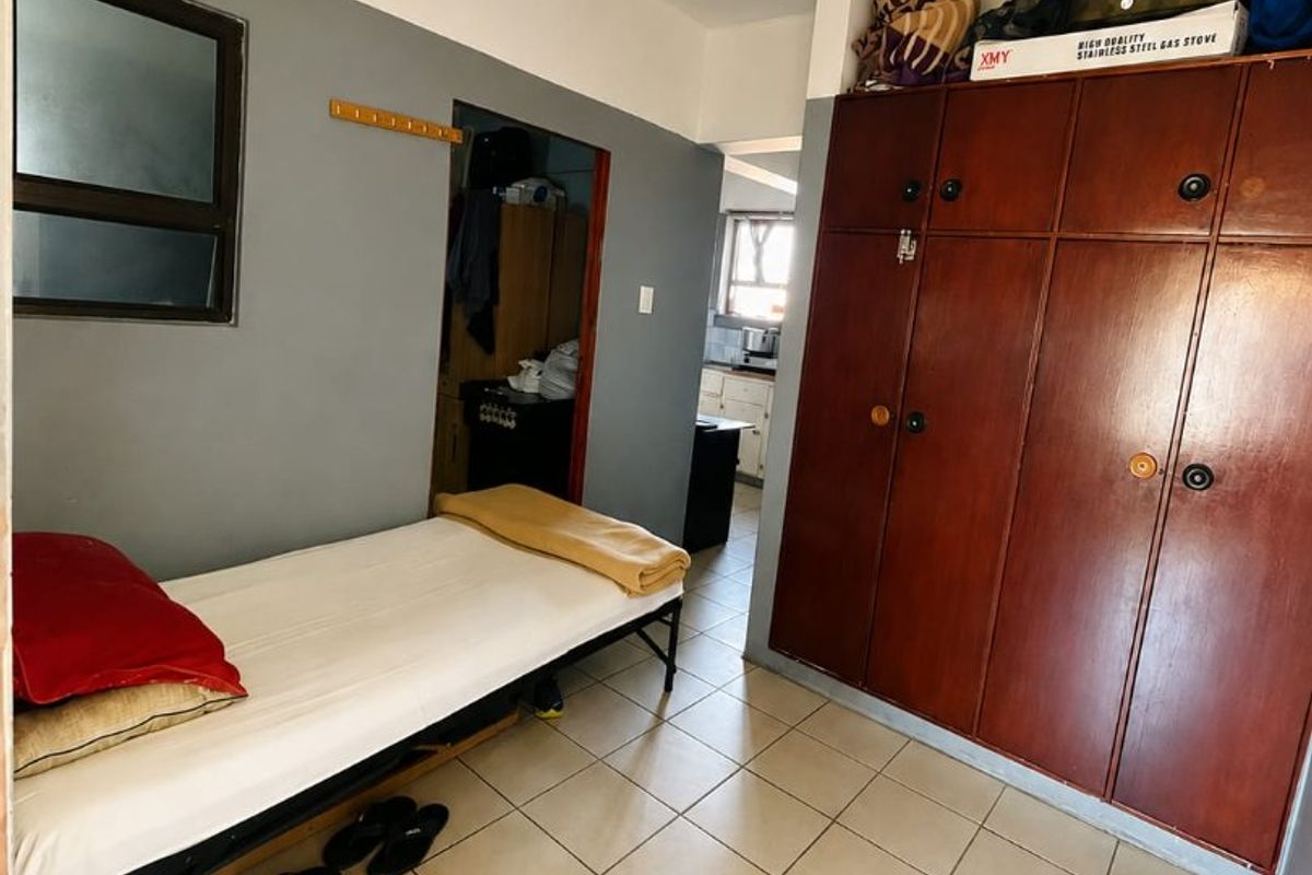 A bedroom featuring tiled flooring and built-in wooden cupboards, providing functional storage space within the apartment.