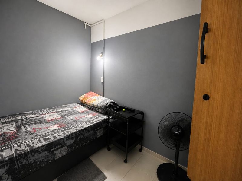 A compact bedroom featuring tiled flooring, a built-in wardrobe, and a wall-mounted light fixture, finished with a two-tone grey and white wall paint scheme.