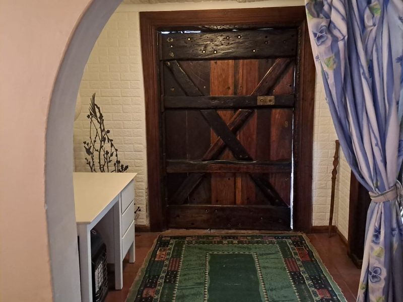 An entryway featuring a rustic heavy timber door framed by an arched opening and textured wall finishes.