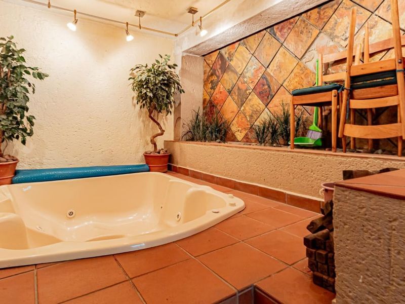 Indoor spa area featuring a built-in jacuzzi, terracotta tiled flooring, and a decorative stone feature wall with integrated lighting.