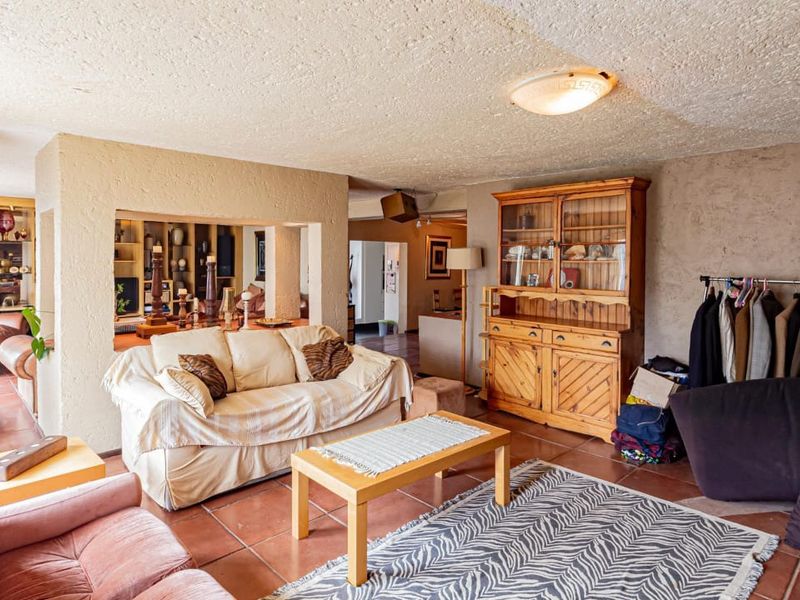 Spacious living area featuring terracotta floor tiles and textured ceilings, offering a dated but functional layout with potential for modern updates.