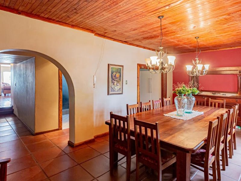 Spacious dining room featuring a warm timber ceiling, terracotta floor tiles, and a classic architectural archway leading to adjacent living areas.