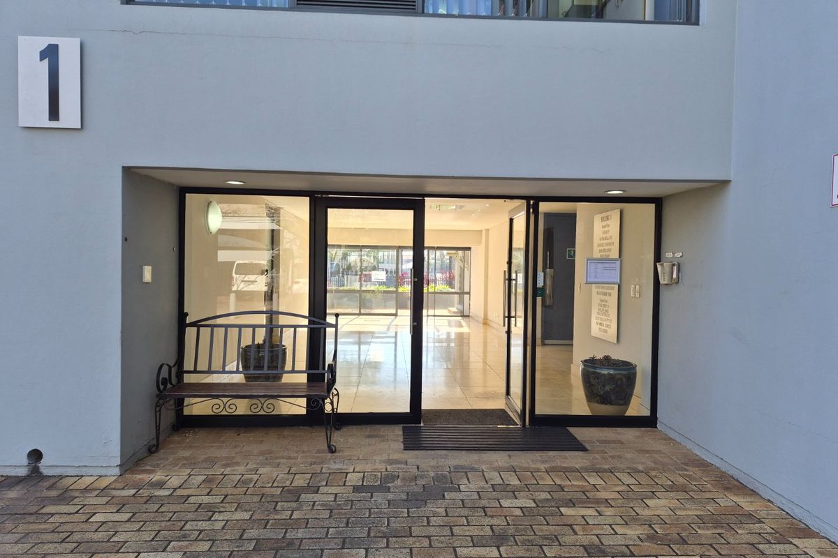Main entrance to commercial building featuring glass doors, paved exterior walkway, and clear signage for building occupants.