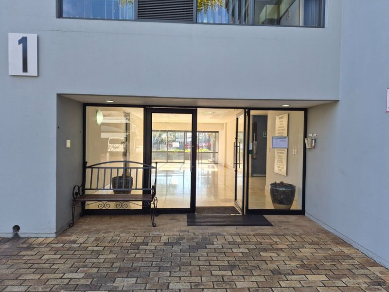 Main entrance to commercial building featuring glass doors, paved exterior walkway, and clear signage for building occupants.