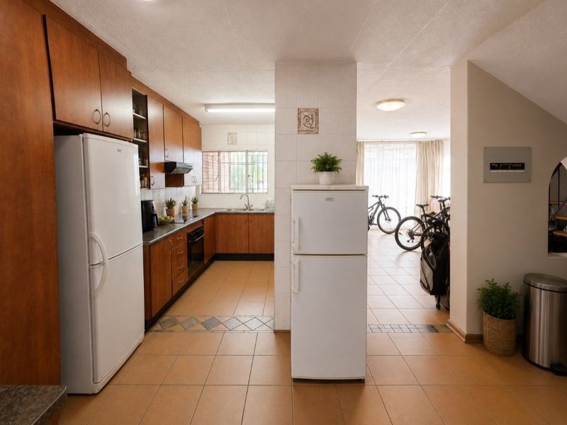 Open plan kitchen featuring wood-finish cabinetry, tiled flooring, and integrated appliances, flowing into an adjacent living area.
