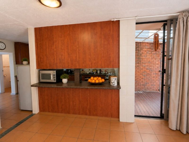 A functional kitchen area featuring wood-look cabinetry, tiled flooring, and direct access to an outdoor patio space through a sliding glass door.