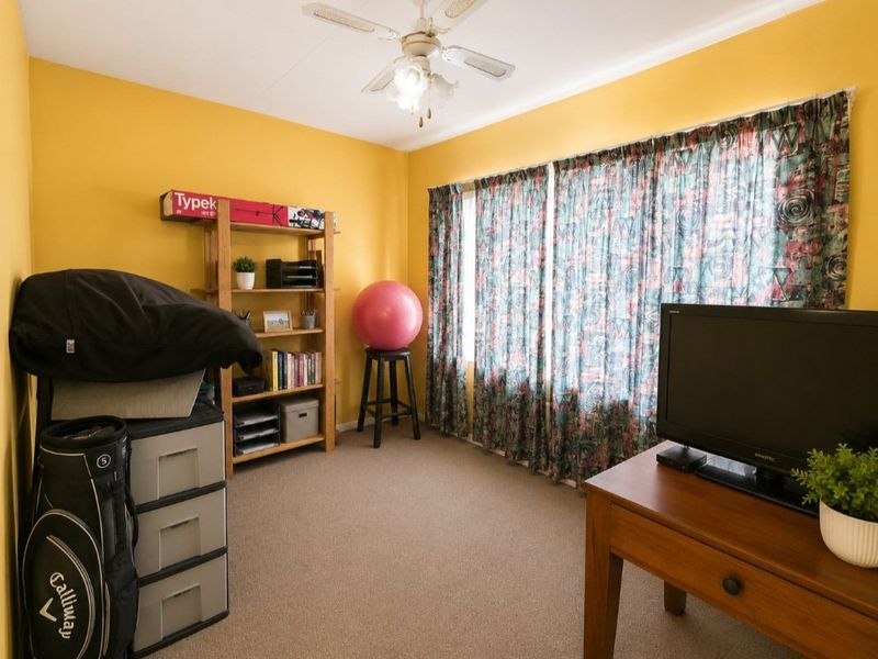 A bedroom featuring carpeted flooring and a ceiling fan, currently utilized as a multi-purpose space.