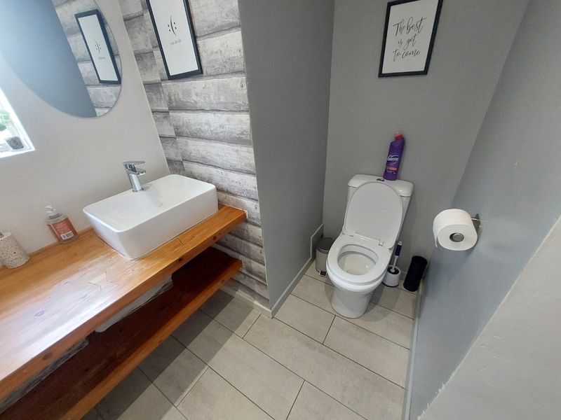 A modern bathroom featuring a vessel sink on a timber vanity, tiled flooring, and a standard toilet.
