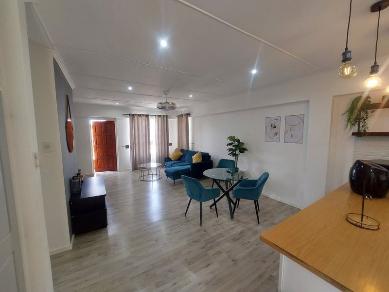 Spacious open-plan living and dining area featuring modern laminate flooring, recessed lighting, and a breakfast bar connecting to the kitchen.