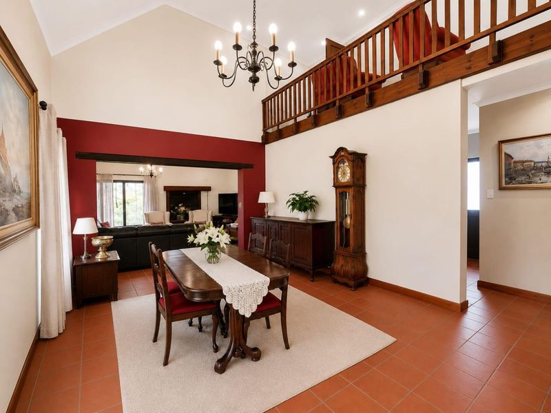 Spacious dining area featuring high vaulted ceilings, terracotta floor tiles, and a mezzanine level with a timber balustrade overlooking the room.